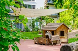 Begrünter Innenhof mit Pergola und Holzhütte.
