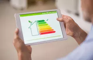 Eine Person hält ein Tablet. Auf dem Bildschirm ist die sehr gute Energieeffizienzbewertung eines Hauses zu sehen.