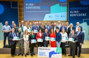 Die Teams der ausgezeichneten Kommunen des Wettbewerbs „Klimaaktive Kommune 2023“ stehen gemeinsam mit den Gratulanten auf der Bühne
