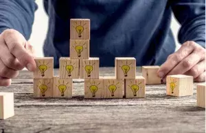 Ein Stapel Holzklötze mit symbolischen Glühbirnen 