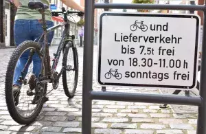 Das Bild zeigt ein Straßenschild und eine Radfahrerin.