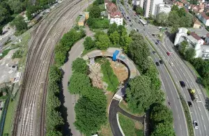 Blick von oben auf Gleise, Bäume und Straßen. Dazwischen der Bau einer neuen Fahrradbrücke.
