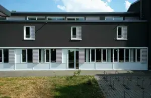 Blick auf ein dunkles Gebäude mit Bäumen davor.