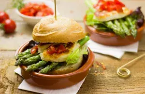 Das Bild zeigt vegetarische Speisen in Schälchen, darunter einen Hamburger mit Spargel.